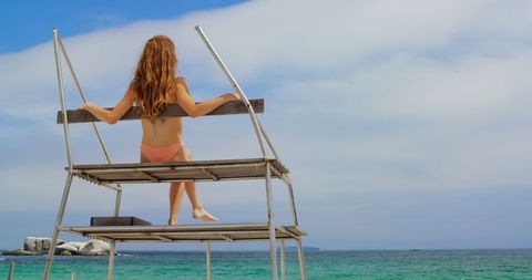 Woman Relaxing on Lifeguard Chair Overlooking the Ocean