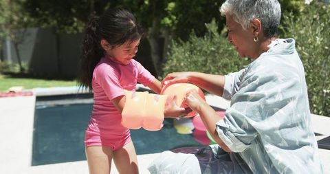 Grandmother and Granddaughter Enjoy Sunny Poolside Water Fun