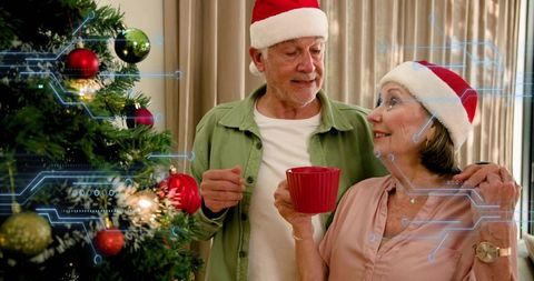 Senior couple wearing santa hats enjoying cozy holiday by decorated tree with tech overlay