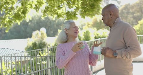 Senior couple enjoying coffee together on sunny balcony