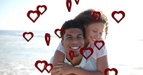 Smiling Couple Enjoying Romantic Beach Day Surrounded by Hearts