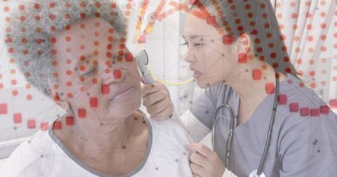 Clinician examining senior patient with otoscope in clinic with medical data overlay