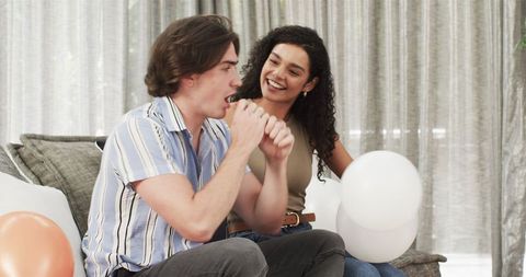 Couple Blowing Up Balloons for Birthday Party Celebration