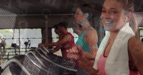 Smiling woman jogging on treadmill with towel and earbuds in busy gym cardio workout