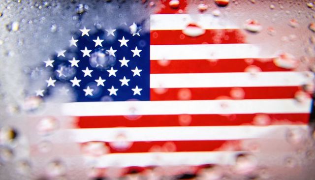 American flag blurring behind wet glass with water droplets and soft bokeh reflections
