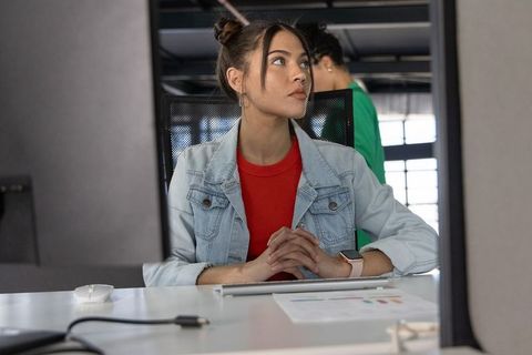 Professional young woman working at open-plan desk reviewing charts and collaborating