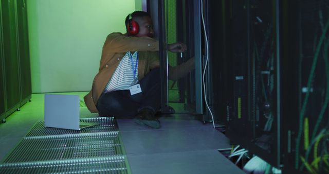 African american male computer technician using laptop working in business server room - Download Free Stock Photos Pikwizard.com