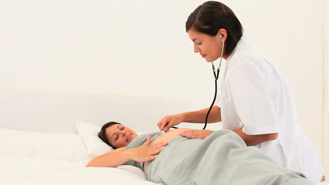Nurse Examining Pregnant Woman at Home
