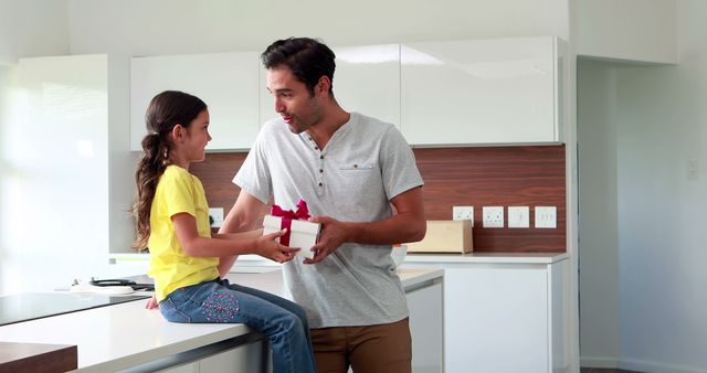 Cute girl giving present to father in the kitchen