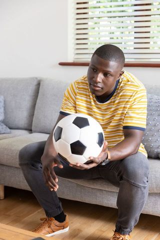 Young Man Contemplating at Home with Soccer Ball
