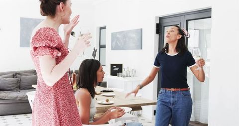 Three Female Friends Celebrating Graduation with Wine in Dining Room