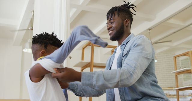 Smiling Father Helping Son with Shirt in Modern Home - Download Free Stock Images Pikwizard.com