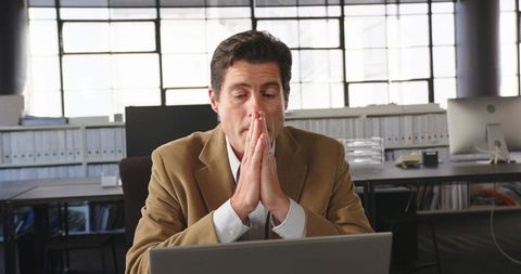 Businessman Deep in Thought Working at Laptop in Modern Office