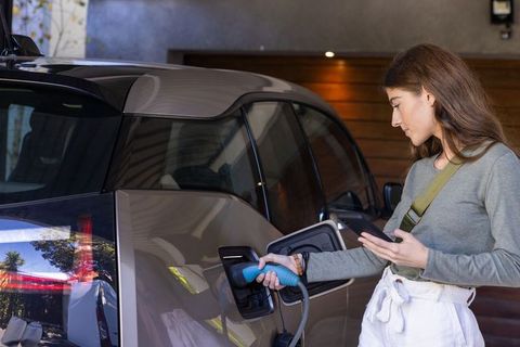 Young woman charging electric car in residential garage
