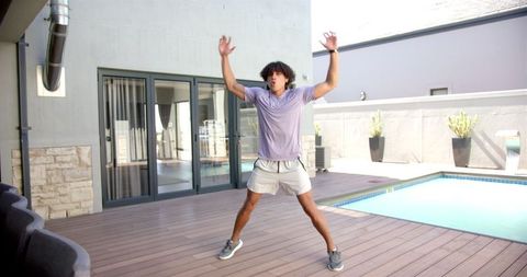 Energetic man performing outdoor jumping jacks by poolside