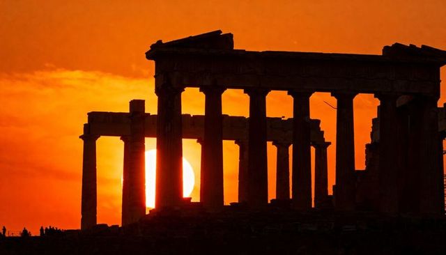 Sunset silhouette of parthenon colonnade with glowing sun between doric columns