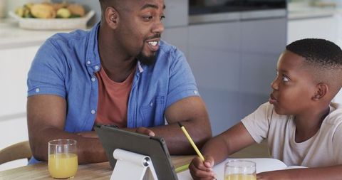 Father Mentoring Son in Homework Using Tablet at Home