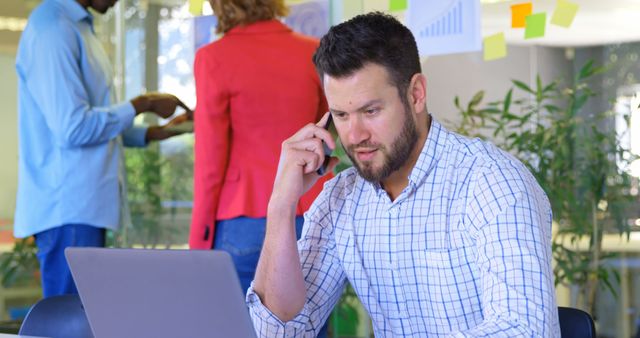 Focused Businessman Talking on Phone and Working on Laptop in Modern Office - Download Free Stock Images Pikwizard.com