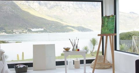 Coastal art studio with wooden easel, green abstract canvas and panoramic sea view