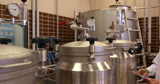 Image depicts stainless steel tanks and pressure gauges within a modern brewery. Ideal for materials focusing on the brewing industry, beer production processes, industrial machinery, and equipment used in microbreweries.