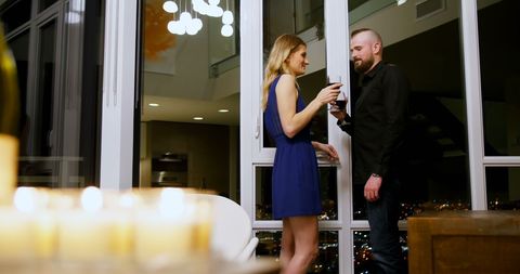 Couple Enjoying Evening Wine Near City View Window