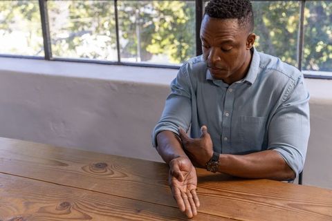 Focused Man Rolling Sleeve While Sitting at Modern Office Table