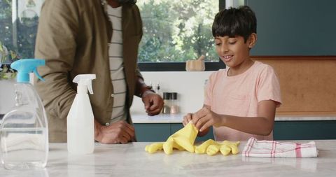 Father and son cleaning together in modern kitchen