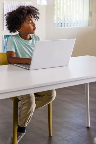 African american boy studying on laptop at minimalist home desk remote learning lifestyle