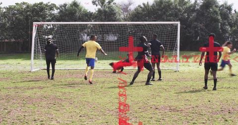 Goalkeeper diving for dramatic save while defenders cluster at goal on grassy park field