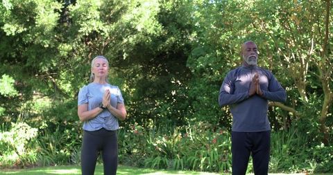 Garden meditation practice: senior man and woman meditating in activewear with smartwatch