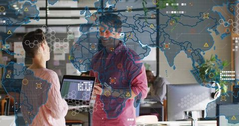 Team collaborating on global data visualization using laptop in modern open-plan office