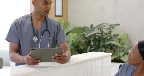 African american medical team collaborating at modern clinic reception with tablet