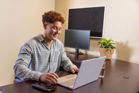 Man smiling while working on laptop in modern office environment
