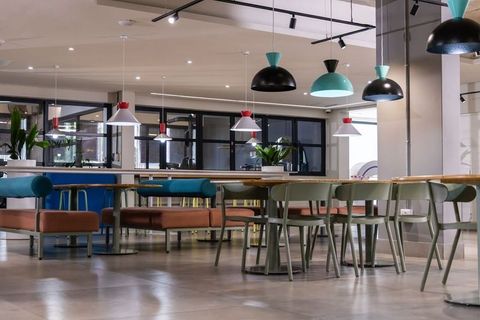 Modern coworking communal dining area featuring long wooden table, bench seating, pendant lights