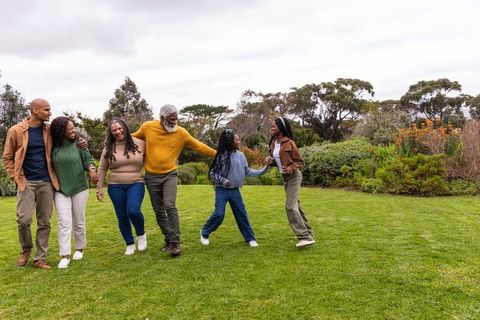 Multigenerational african american family walking holding hands in park on overcast day