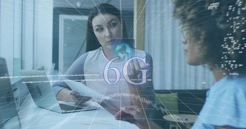 Businesswomen collaborating over documents and laptop with 6g network visualization, insights