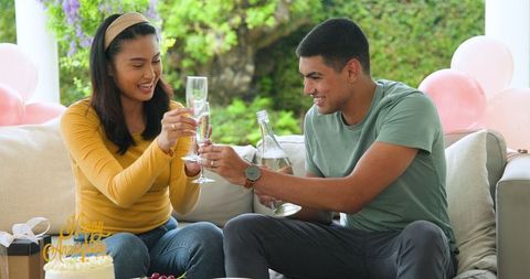 Young Couple Celebrating Anniversary with Champagne on Cozy Sofa