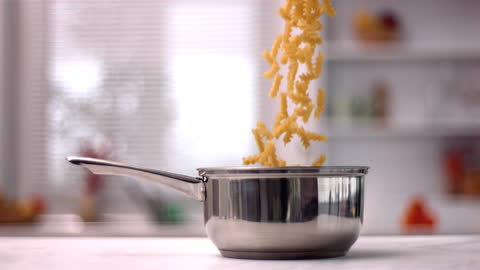 Slow Motion Fusilli Falling into Saucepan in Modern Kitchen