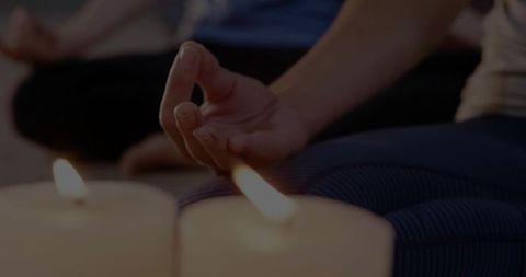 Woman meditating with mudra and candlelight creating calm mindfulness and relaxation