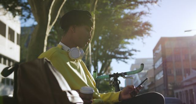 Young man with headphones using smartphone and drinking coffee outdoors - Download Free Stock Images Pikwizard.com