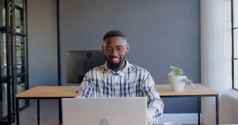 African American Man Smiling While Using Laptop at Office Desk - Download Free Stock Images Pikwizard.com