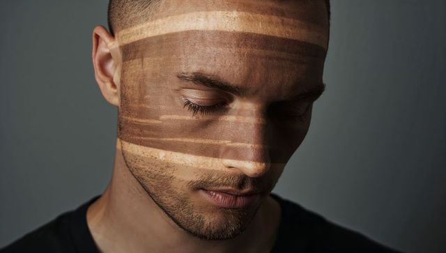 Contemplative man with horizontal light bands on face closeup portrait dramatic low-key