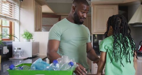 Father and Daughter Sorting Bottles for Recycling at Home