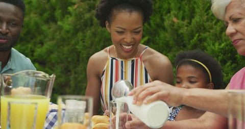 Diverse Family Sharing Joyful Breakfast Outdoors in Sunny Garden