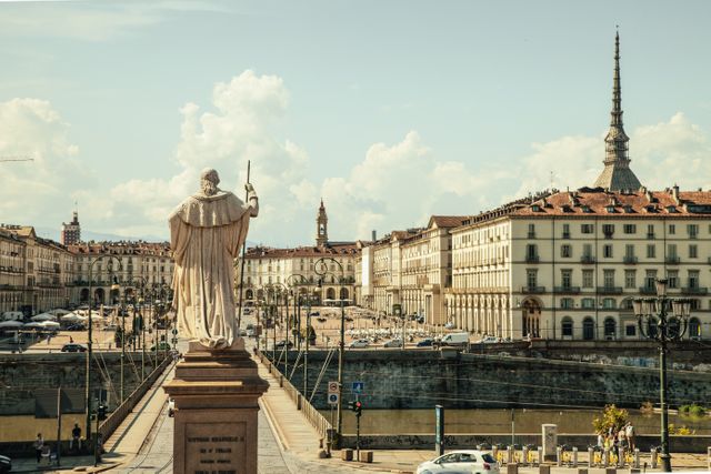 Monument in foreground overlooks an expansive historic Italian cityscape. Prominent landmark in distance contributes to iconic view. Ideal for use in travel brochures, cultural heritage presentations, and articles exploring Italian architecture and urban life.