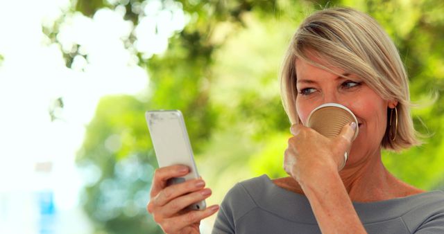 Woman using smartphone while drinking coffee