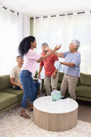 Multigenerational family embracing and laughing during home reunion in sunlit living room