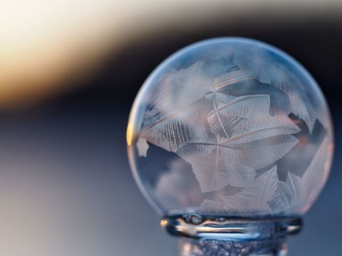 Frost patterns inside frozen soap crystal ball at sunrise