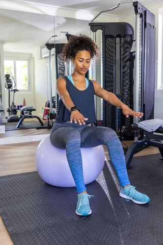 Woman practicing balance on stability ball in home gym