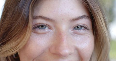 Smiling young woman showing freckles and hoop earring closeup natural soft light portrait